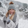Conception of winter holidays. Cheerful girl in warm clothes playing with snow outdoors near the beautiful forest