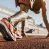 Close up of male athlete getting ready to start running on track . Focus on sneakers