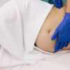 Physiotherapist woman massaging tummy on pregnant woman on a stretcher. Pregnant woman visit gynecologist doctor at hospital or medical clinic for pregnancy consultant. Gynecology concept