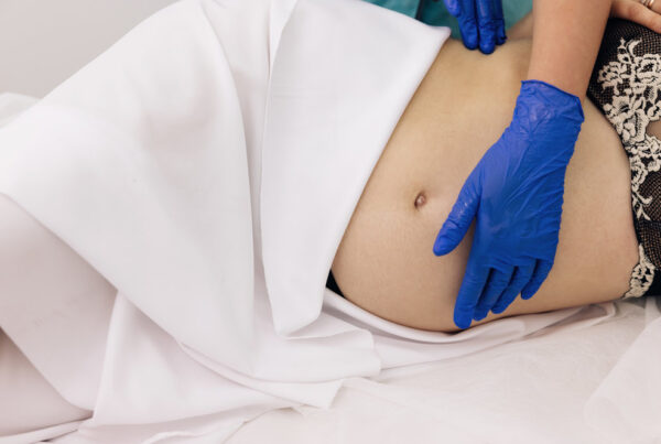 Physiotherapist woman massaging tummy on pregnant woman on a stretcher. Pregnant woman visit gynecologist doctor at hospital or medical clinic for pregnancy consultant. Gynecology concept