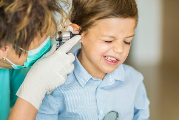 Little boy uncomfortable as he gets his ears checked by the doctor