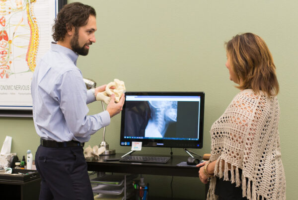 The chiropractor shows the client a model of the vertebrae.