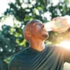 Fitness, black man and drinking water outdoor for health, wellness and exercise recovery.