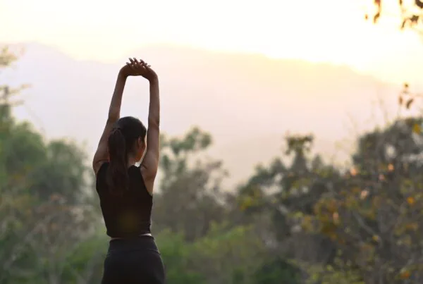 Woman stretching outdoors at sunset as part of a holistic summer wellness routine in Bend Oregon